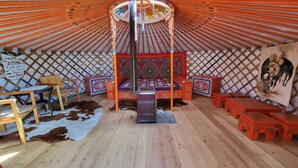 A yurt interior with a central bed, wooden furniture, and a decorative wall hanging. - Ulaanbaatar (Erdene)