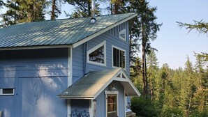 A two-story house with a garage, a small porch, and outdoor seating. - Charming house with orchard and pond close to Flathead Lake (Rollins)