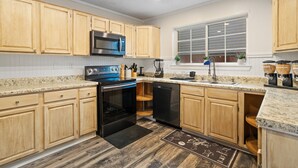 A modern kitchen with wooden cabinets, stainless steel appliances, granite countertops, and a window with blinds. - Beautiful Luxury Budget Home With Pool. Near 6Flags / AT&T (Grand Prairie)