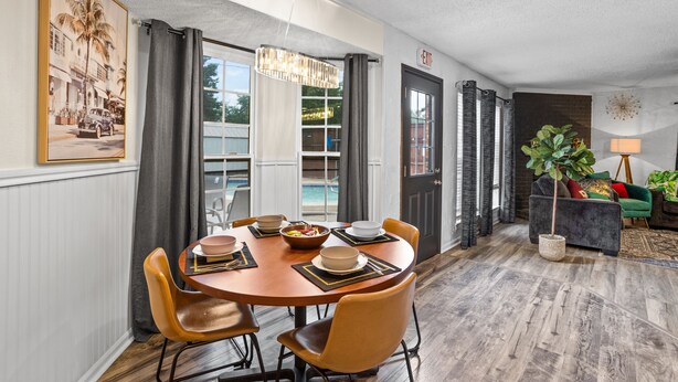 A dining area with a wooden table, chairs, and a chandelier. There is a view of a pool through large windows. - Beautiful Luxury Budget Home With Pool. Near 6Flags / AT&T (Grand Prairie)