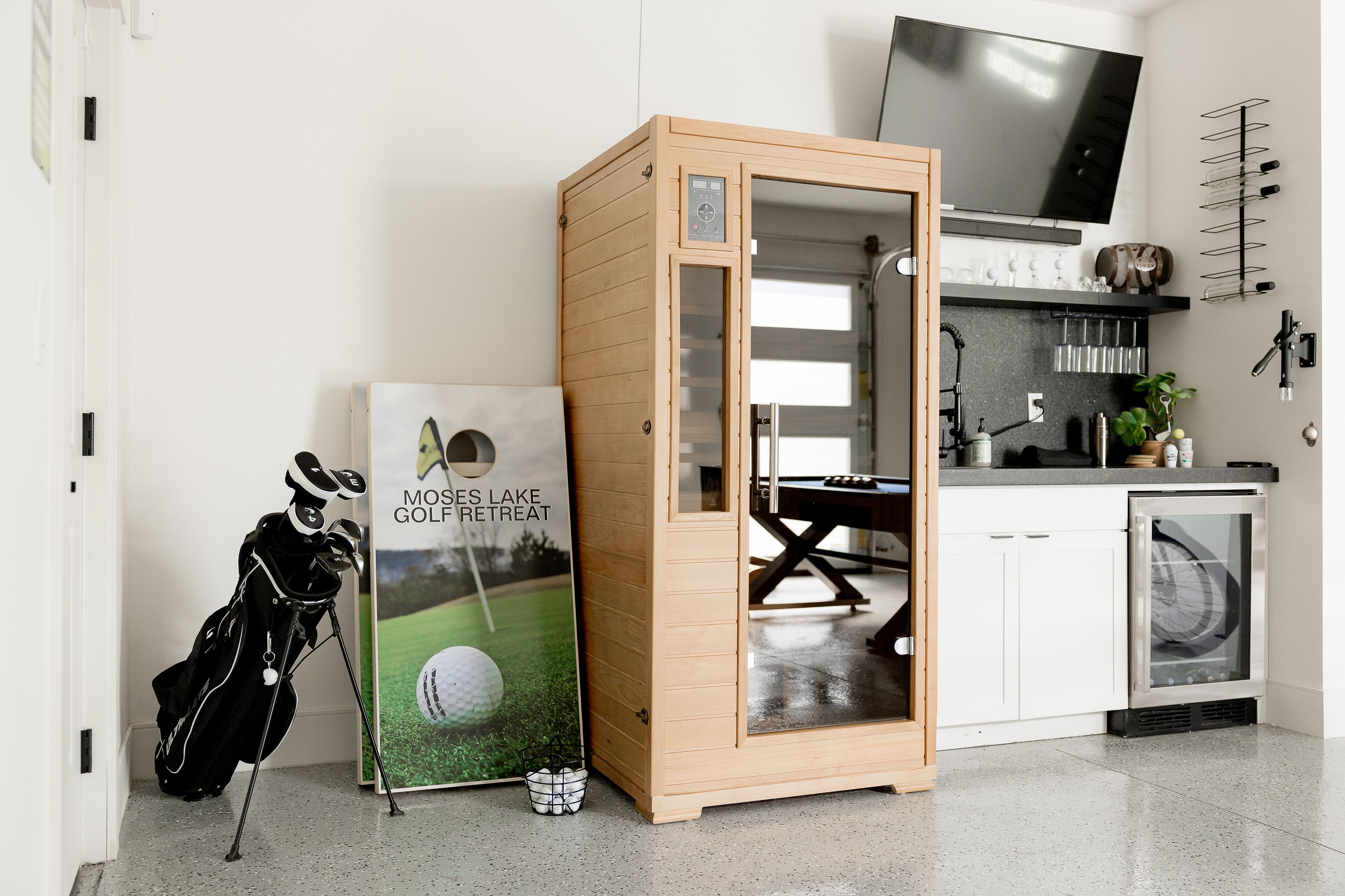A modern kitchen with a wooden cabinet, a TV, and a golf-themed poster.