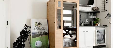 A modern kitchen with a wooden cabinet, a TV, and a golf-themed poster.