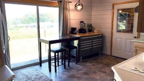 A kitchen with a large window, a countertop with a blender, and a cabinet with drawers.