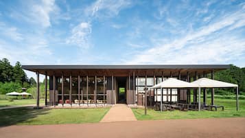 Un bâtiment moderne doté d’un patio couvert, d’un espace extérieur aménagé pour s’asseoir et d’un chemin menant à l’entrée.