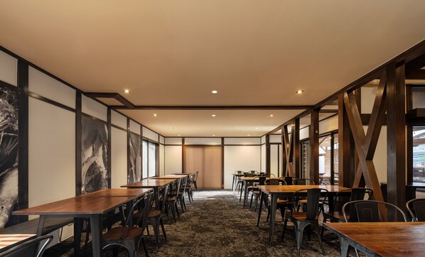 A conference room with long tables and chairs, wooden floors, and large windows.