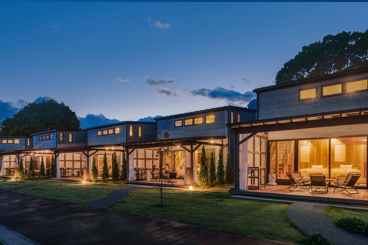 Un edificio residencial moderno con varias unidades conectadas, cada una con grandes ventanales y espacios al aire libre para sentarse.