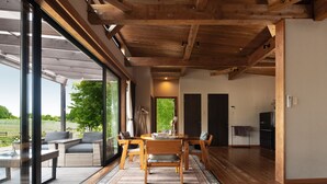 Una habitación amplia con techo de madera, ventanas grandes y un comedor con mesa y sillas.