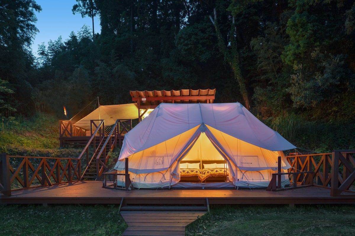 Una gran carpa con una terraza de madera y una escalera que sube a un nivel superior.