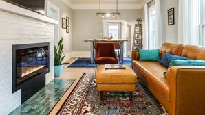 A living room with a fireplace, a sofa, a coffee table, and a dining area with a table and chairs.