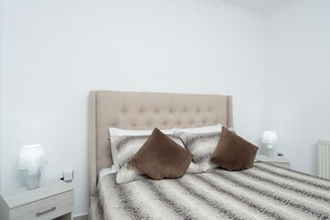 Restful retreat with a large bed, nightstand, and tufted headboard.