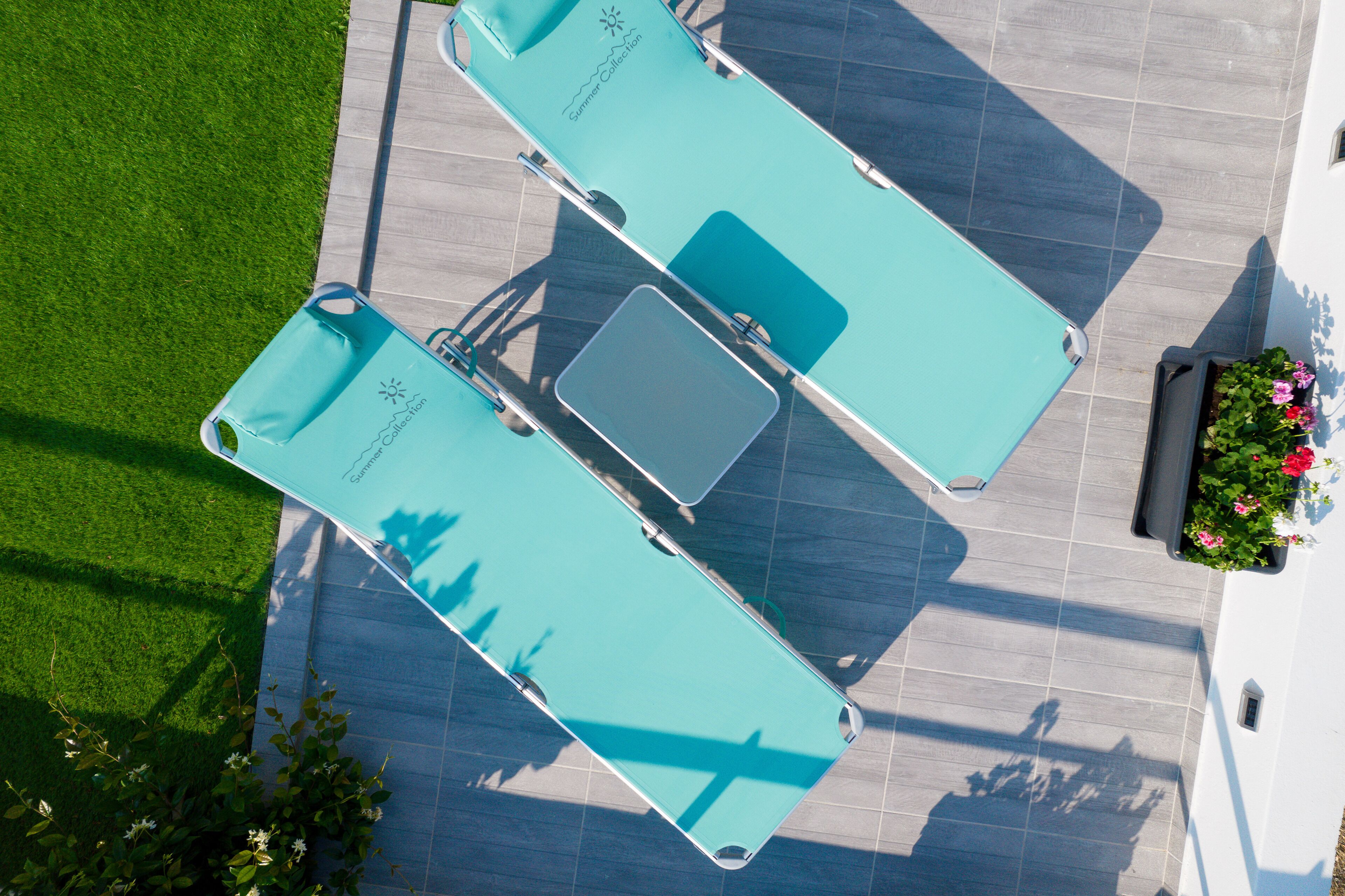 An aerial view of a pool area with two sun loungers and a small table.