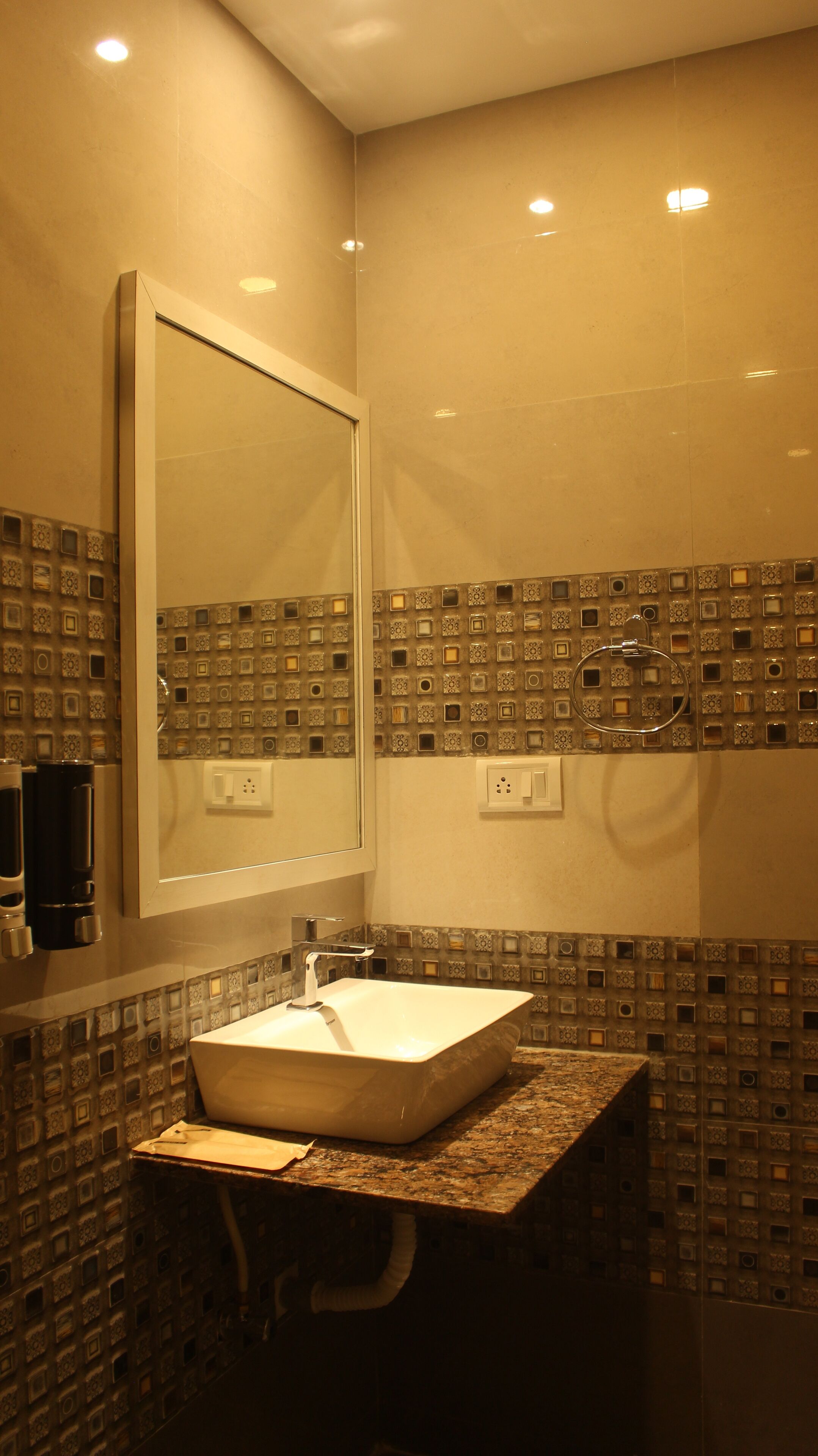 Une salle de bain avec un grand miroir, un lavabo et des carreaux décoratifs sur les murs.