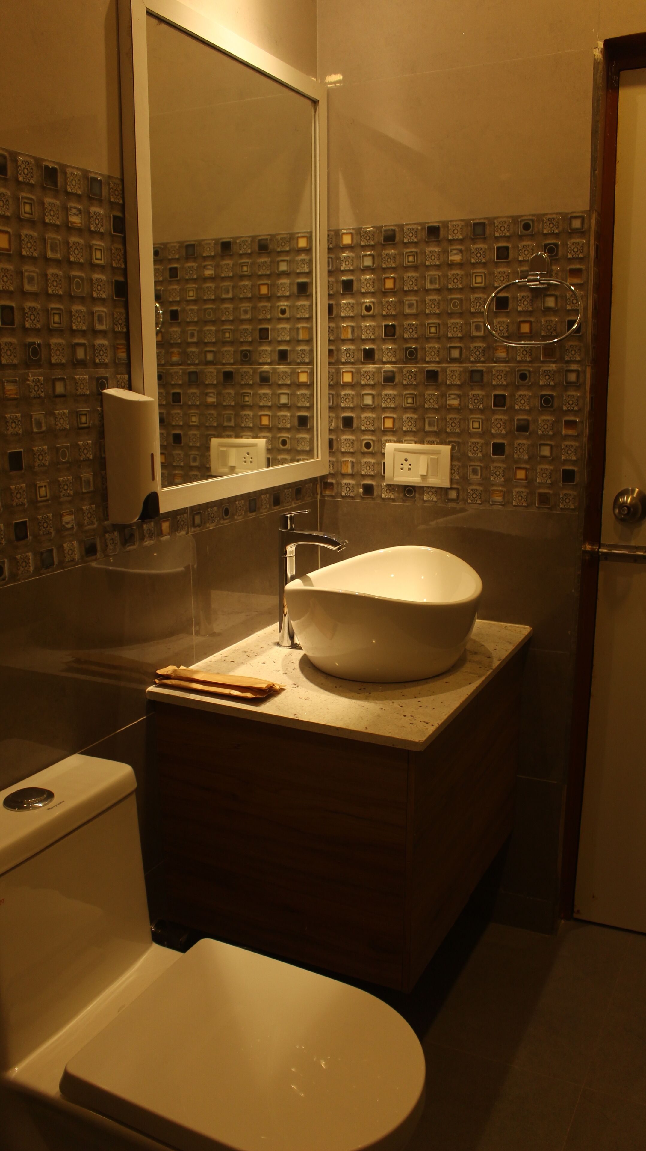 A bathroom with a white sink, a mirror, and a patterned wall.