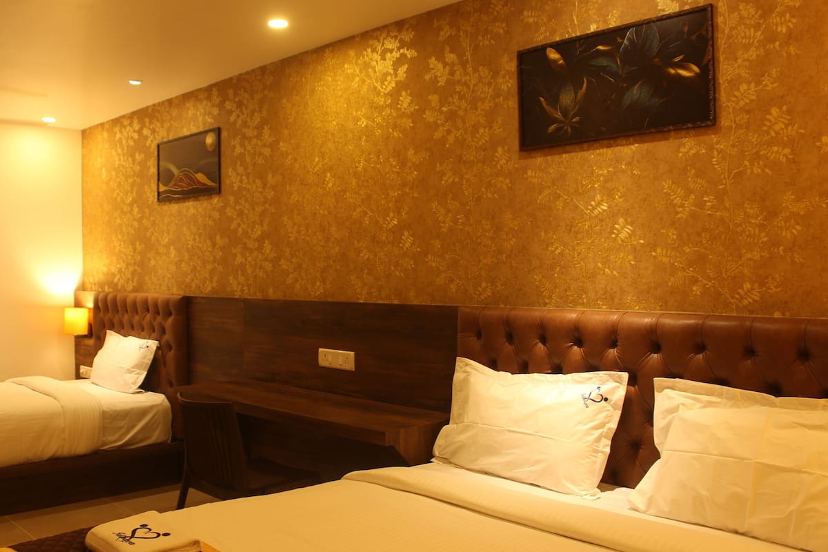 A hotel room with two beds, a wooden headboard, and a wall with floral wallpaper.
