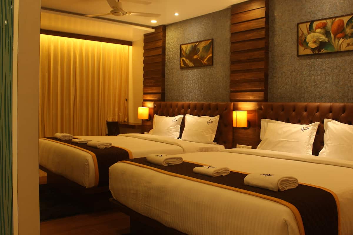 A hotel room with two beds, each with a headboard, bedside lamps, and towels.