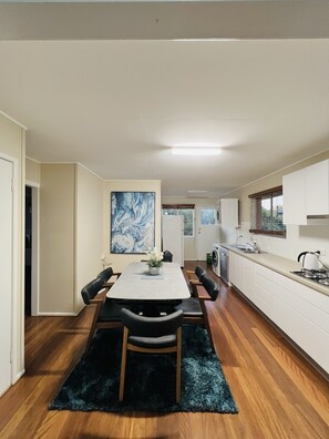 Modern kitchen and dining area with a gas stove, stainless steel sink, and a dining table for six.