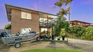 Une maison moderne à deux étages, avec un bateau amarré à l’extérieur.
