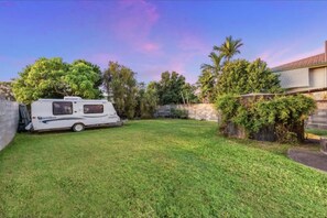 Enjoy a serene outdoor space with a well-manicured lawn, garden, and a charming RV.