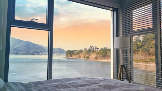 Ein Schlafzimmer mit einem großen Fenster, das Blick auf einen See und Berge bietet.