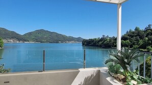 Ein Balkon mit Blick auf einen stillen See und Berge.