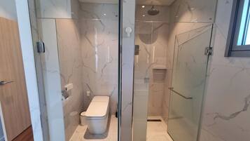 Un baño moderno con ducha de vidrio, inodoro y suelo de mármol.