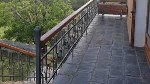 A balcony with a stone floor, metal railing, and a bench. It overlooks a mountainous landscape with trees. - House overlooking the Cadí-Moixeró massif, traditional from the 70s with magical (Lles de Cerdanya)