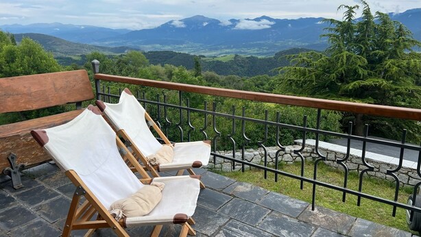 Two wooden lounge chairs with white cushions on a stone-tiled balcony overlooking a mountainous landscape. - House overlooking the Cadí-Moixeró massif, traditional from the 70s with magical (Lles de Cerdanya)