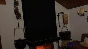 A traditional fireplace with a black mantel, a hanging pot rack, and a rustic wooden floor. - House overlooking the Cadí-Moixeró massif, traditional from the 70s with magical (Lles de Cerdanya)