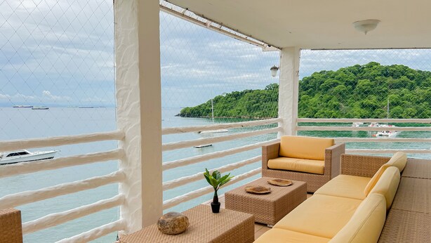 A balcony with wicker furniture and a view of the sea. - Live an Adventure in Taboga 2 (Provincia de Panamá)