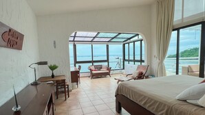 A hotel room with a bed, a desk, a chair, and a view of the sea. - Live an Adventure in Taboga 2 (Provincia de Panamá)
