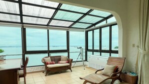 A room with a large window overlooking a body of water, a tripod, and two wooden chairs. - Live an Adventure in Taboga 2 (Provincia de Panamá)