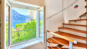 A staircase with wooden steps and metal railings, leading to a balcony with a view of mountains and a body of water. - Villa Il Paradiso Di Gabri: Lake-view Villa With Garden (Nago-Torbole)