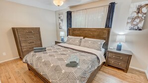 A bedroom with a large bed, wooden nightstands, a dresser, and a ceiling fan.