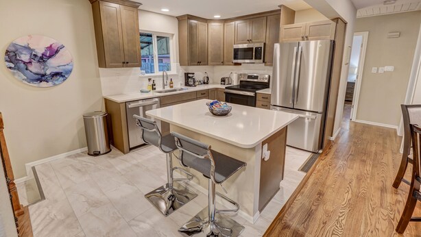 A modern kitchen with wooden cabinets, stainless steel appliances, and a central island with bar stools.
