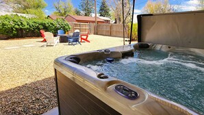 A hot tub with a control panel, surrounded by a gravel patio and outdoor furniture.