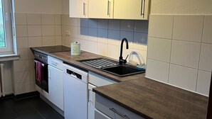 Una cocina moderna con armarios blancos, un grifo negro y una encimera de madera.