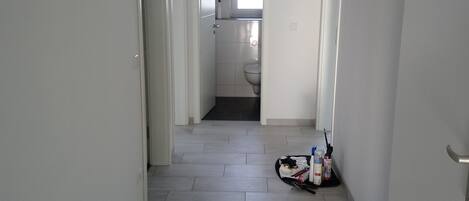 A hallway with grey tiled flooring, white walls, and doors leading to other rooms.