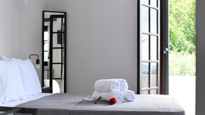 A neatly made bed with white linens, a rose on the bed, and a view of greenery through an open window. - Relaxing villa with amazing view (Garazo)
