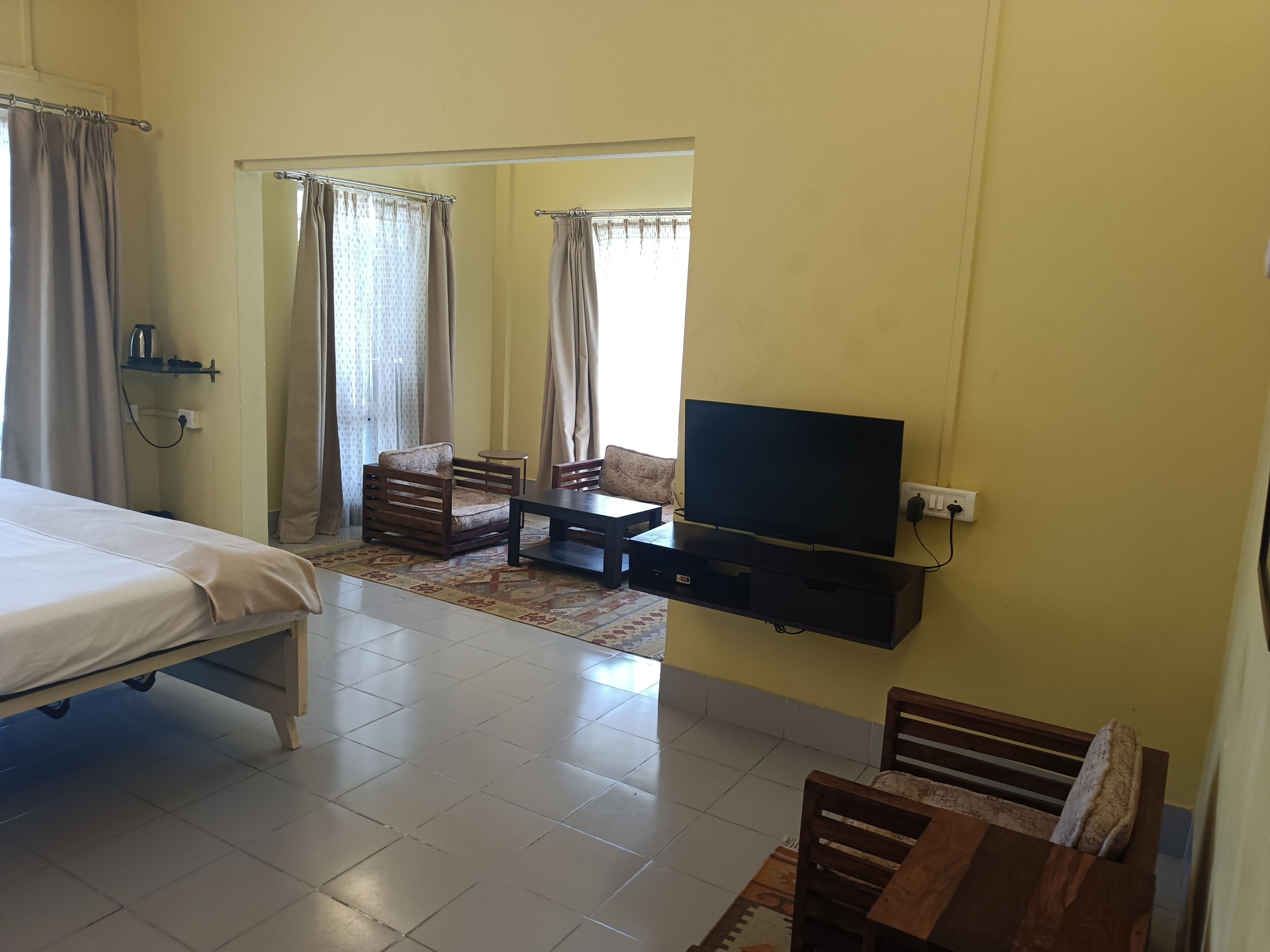 A hotel room with a bed, a TV mounted on the wall, a small table, and a sofa.