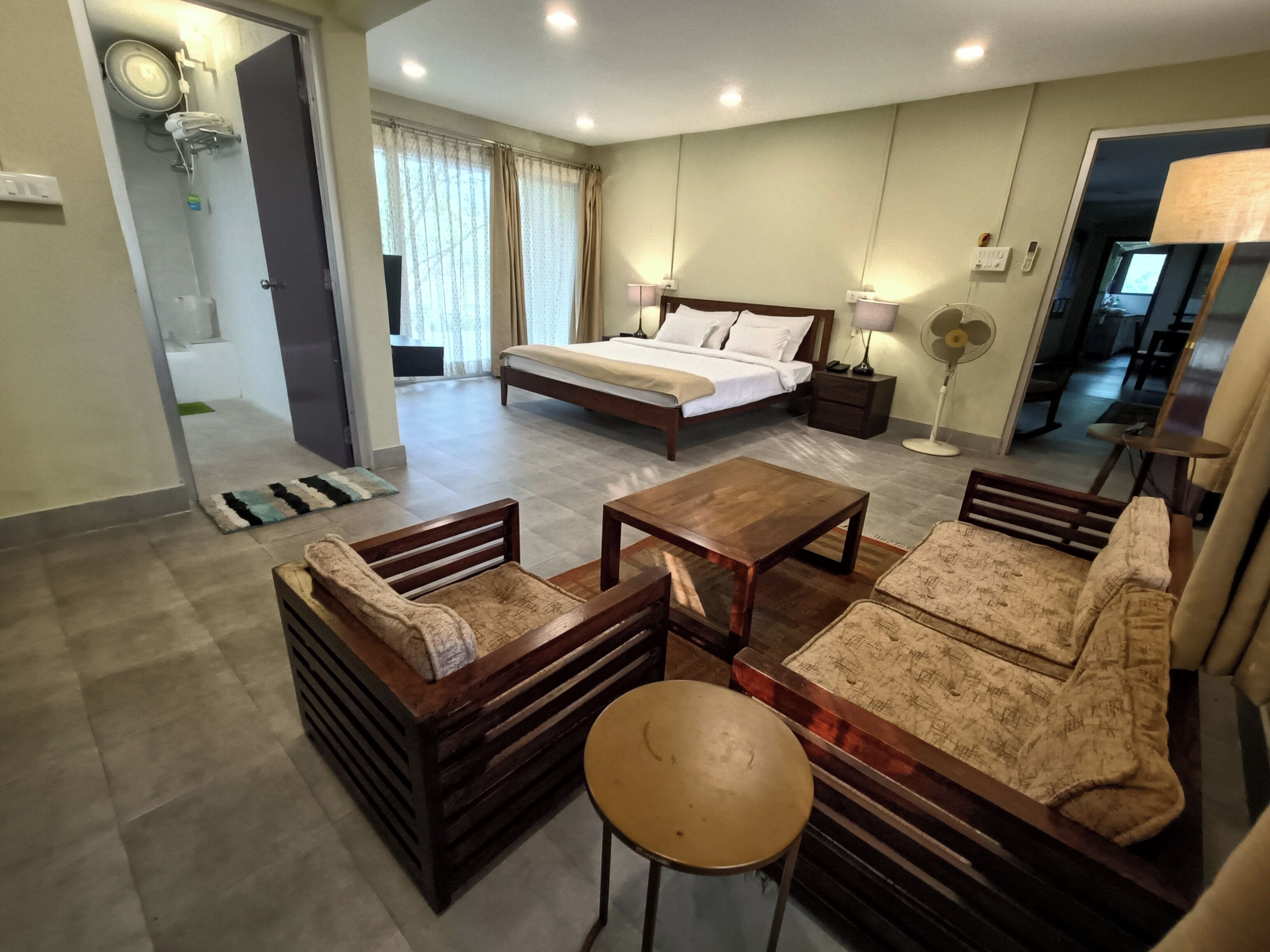 Hotelkamer met een bed, twee nachtkastjes, een bijzettafeltje, een bank, een stoel en een klein rond tafeltje.