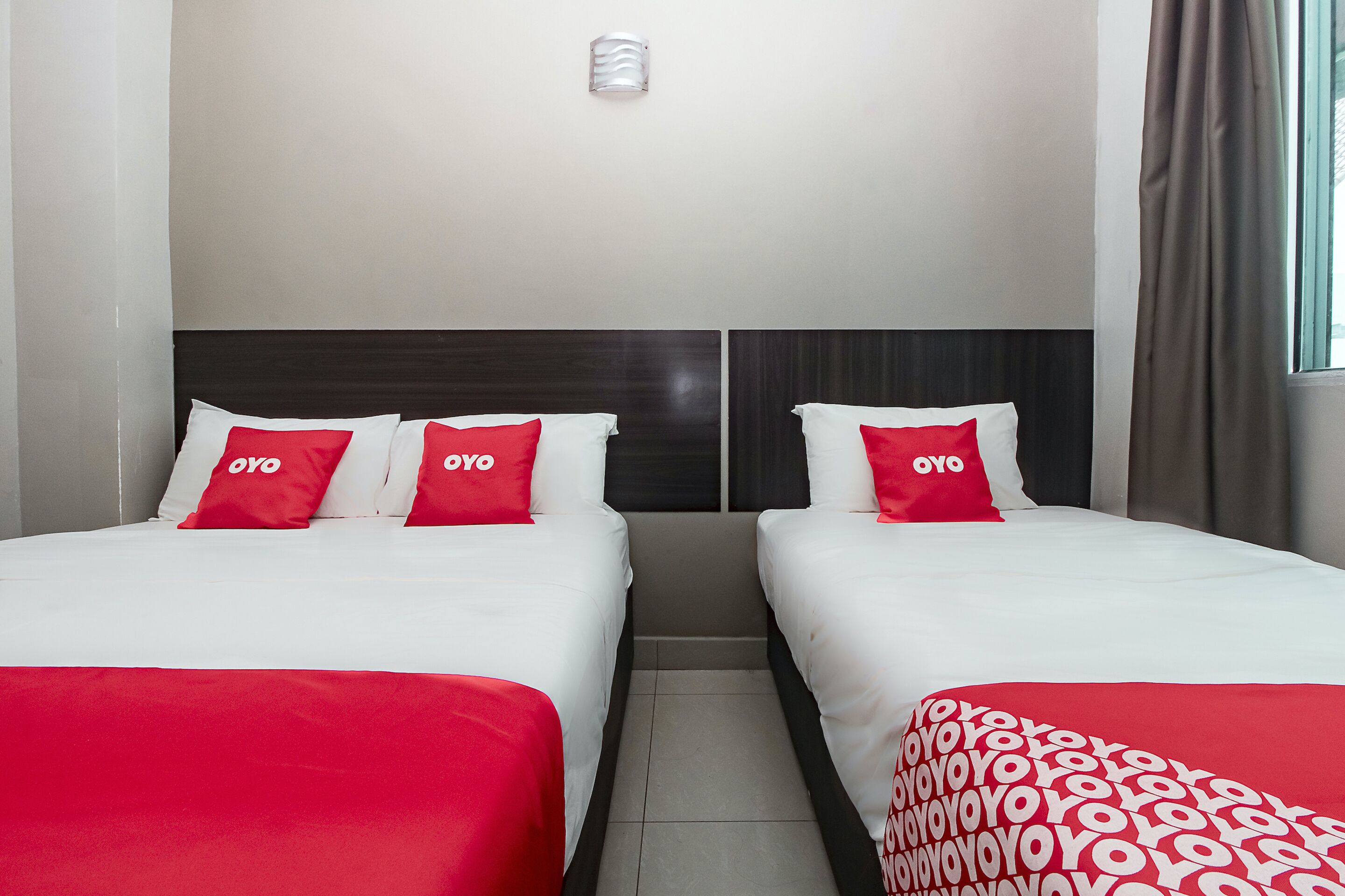 A hotel room with two beds, each with white bedding and red pillows.
