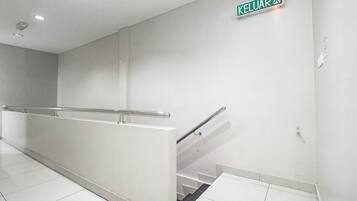 A clean, modern stairwell with a metal handrail and a sign indicating the direction to the elevator.