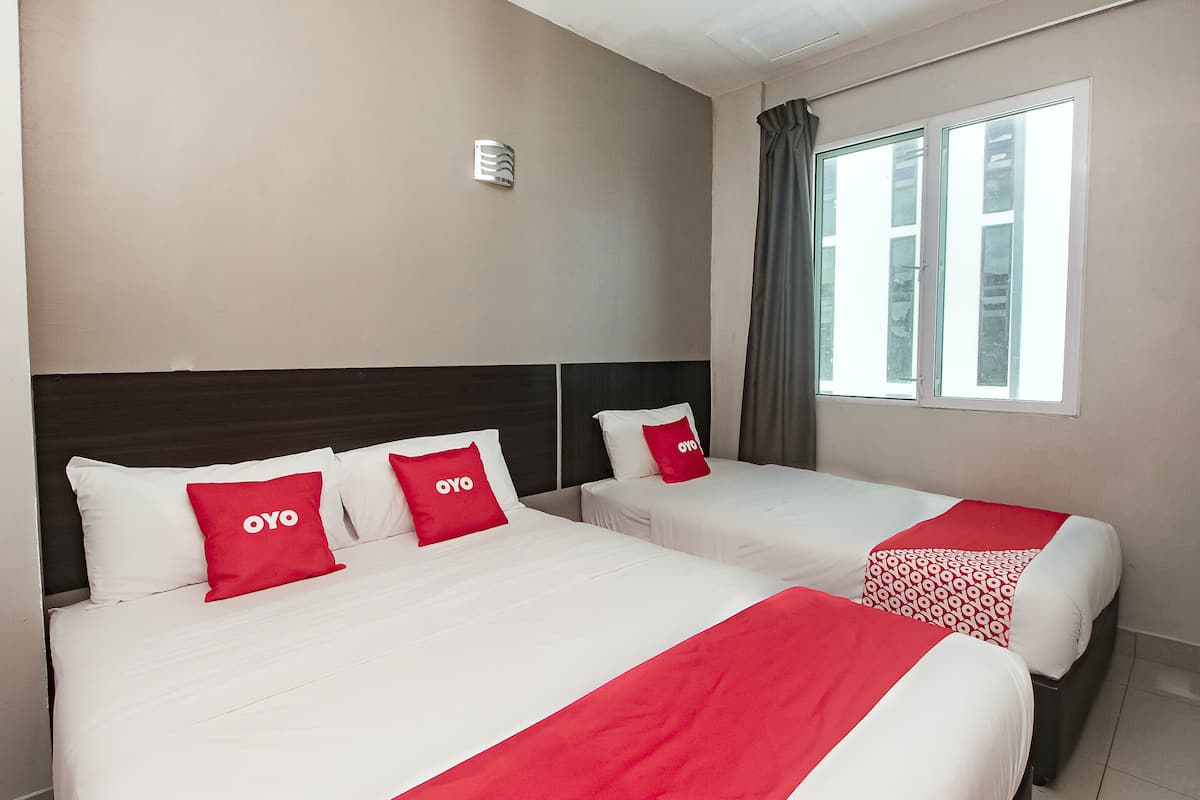 A hotel room with two beds, each with white bedding and red pillows.