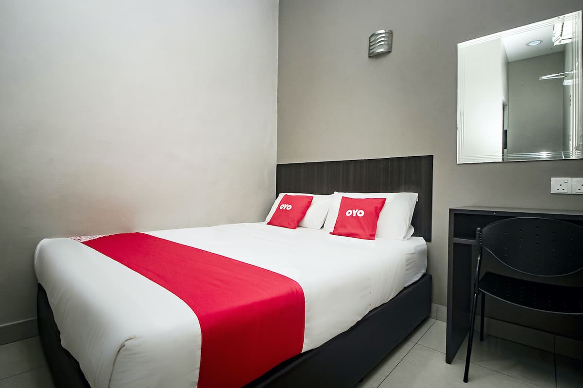 A hotel room with a bed, a desk, and a chair.