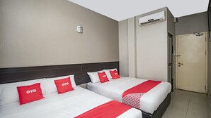 Duas camas com roupa de cama vermelha e branca, uma porta branca e um aparelho de ar condicionado fixado na parede.
