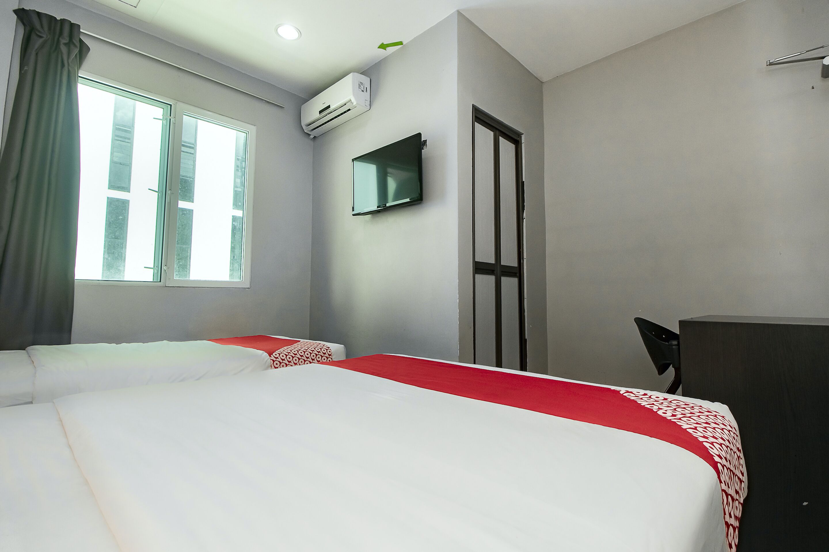 Une chambre d’hôtel avec un lit, une télévision, un bureau et une fenêtre avec des rideaux.