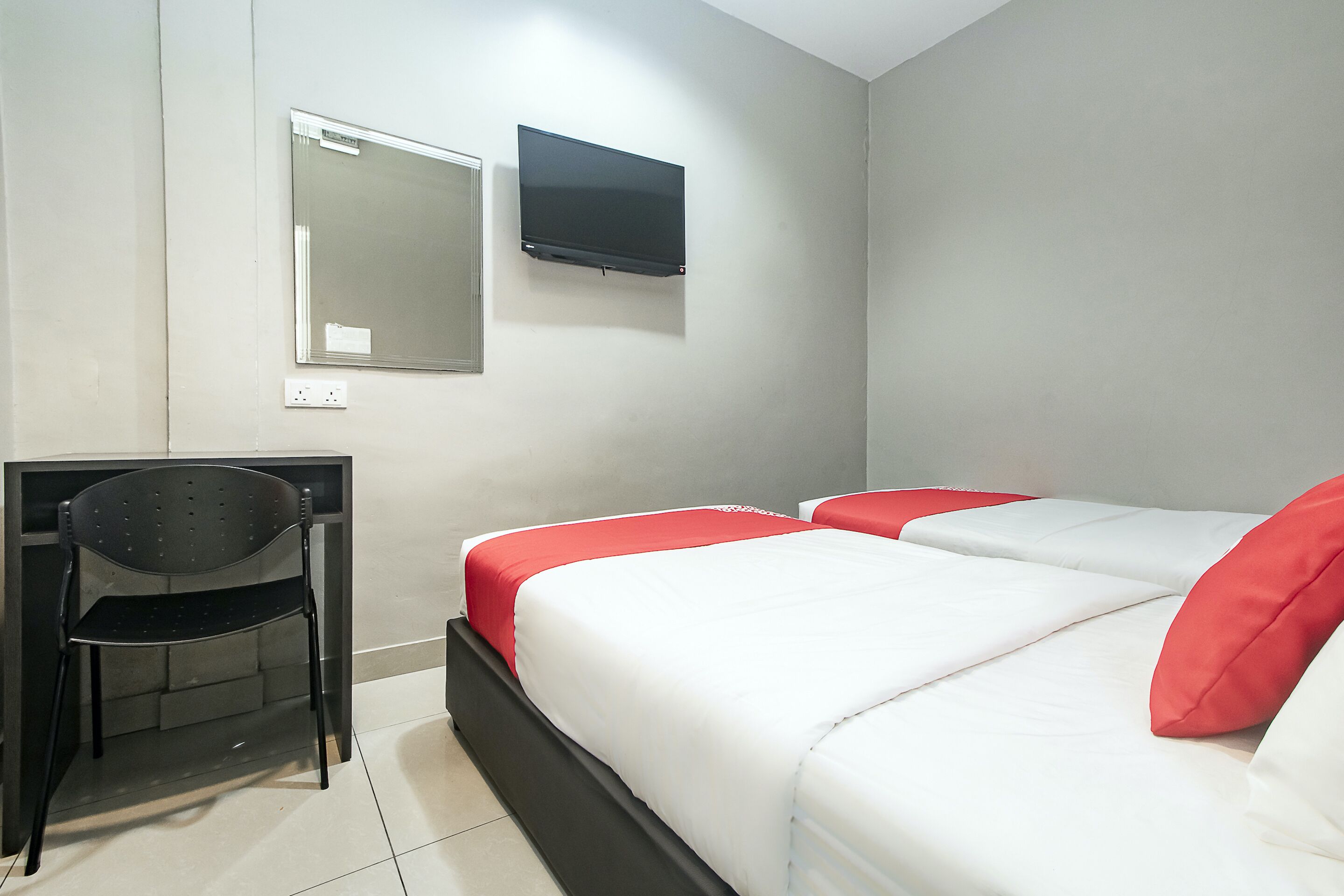 Une chambre d’hôtel équipée d’un lit, d’un bureau, d’une chaise et d’un téléviseur fixé au mur.
