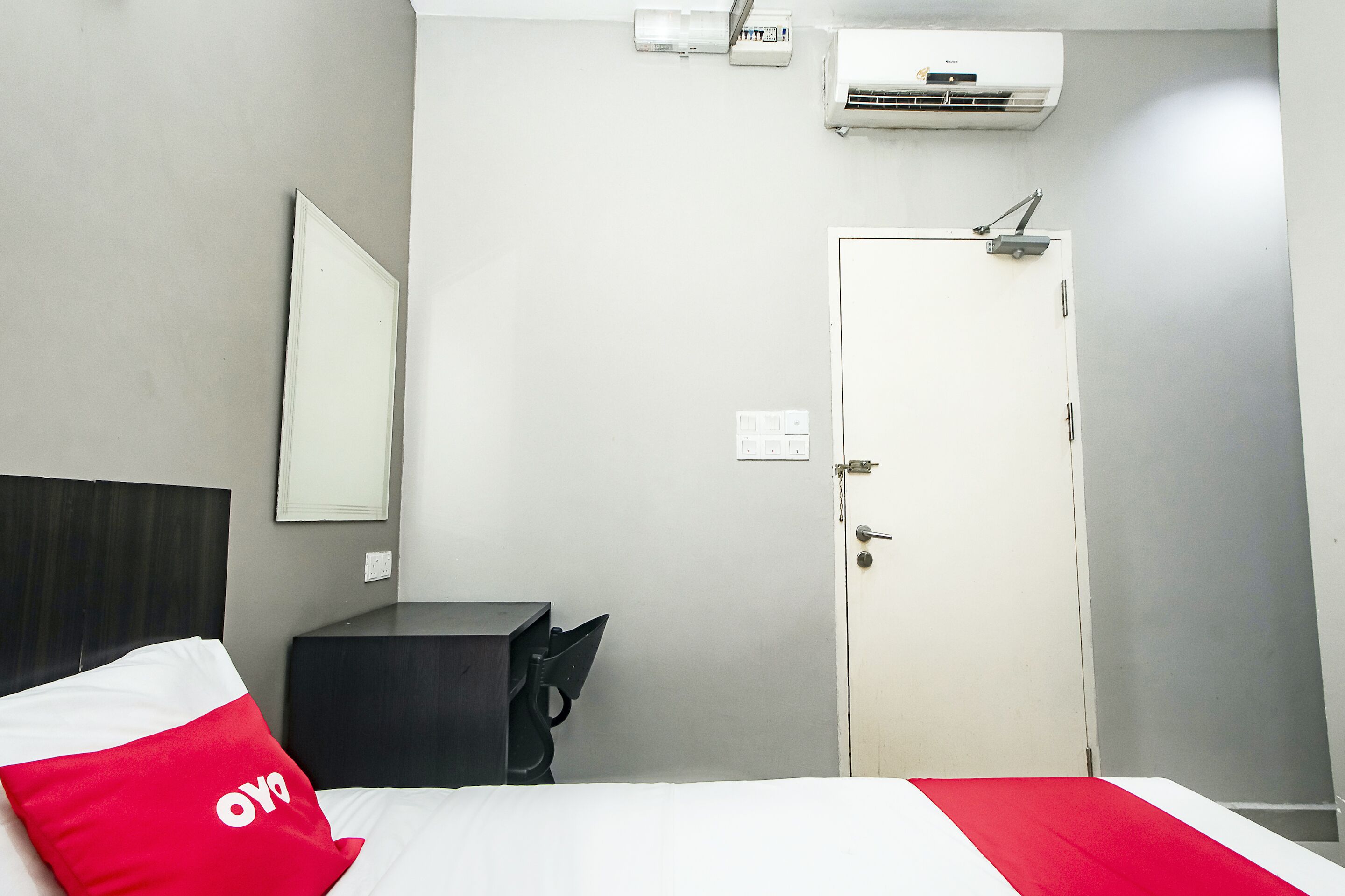 Une chambre d’hôtel équipée d’un lit, d’un bureau, d’une chaise, d’une armoire, d’une porte et d’un appareil de climatisation.