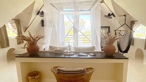 A cozy, triangular room with a central island, a hanging chair, and a hammock. - Kuwa Zanzibar (Kiwengwa)