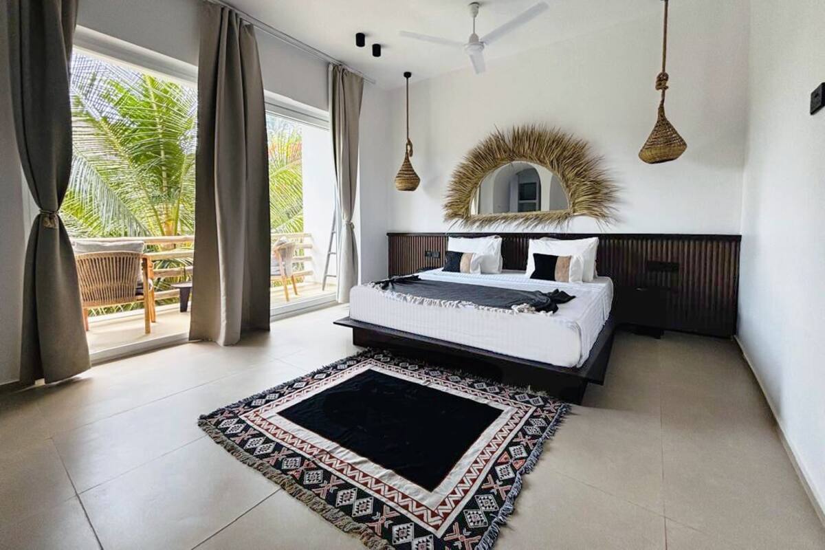 A bedroom with a bed, a large mirror, and a view of the outdoors.